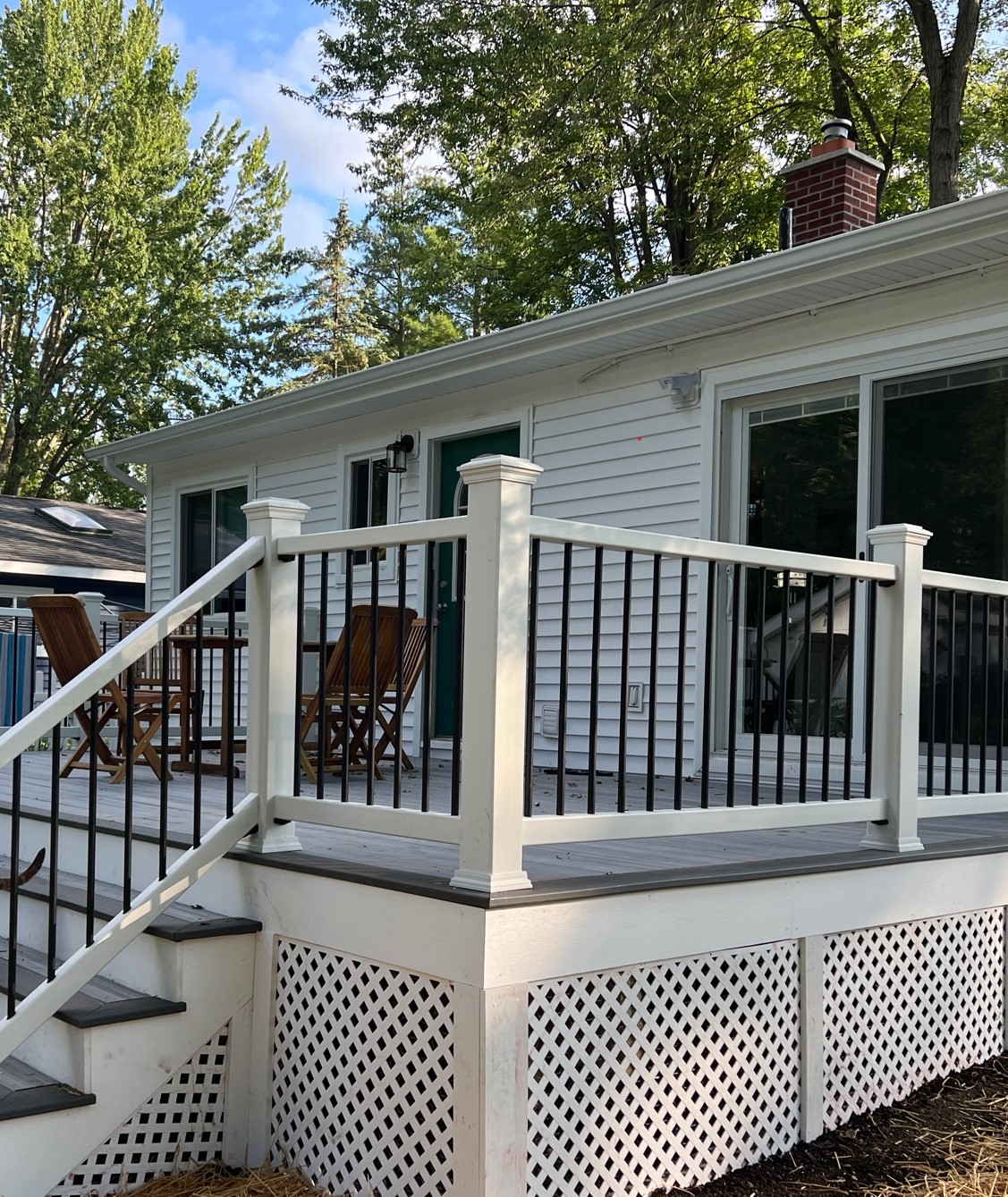 A newly repaired composite deck with a black metal rail and white balusters.